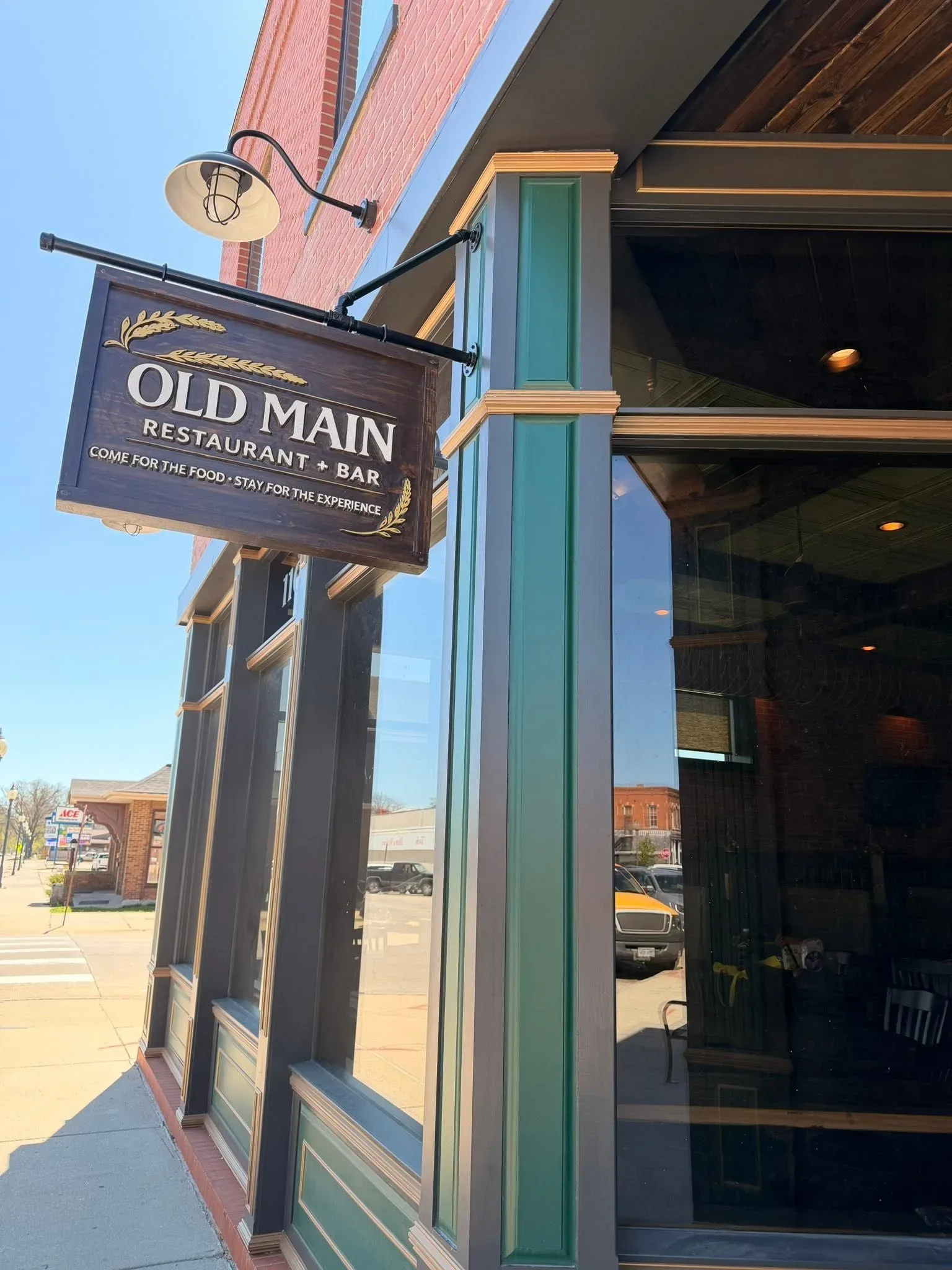 The hanging Old Main Restaurant + Bar sign against the brick facade on Main Street in Crete, Nebraska